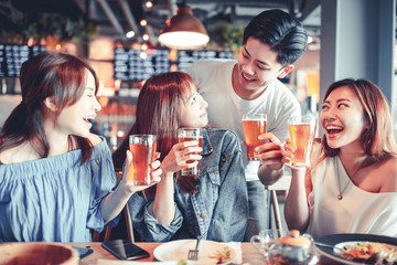 happy young group dining and drinking beer at restaurant
