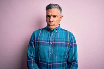 Middle age handsome grey-haired man wearing casual shirt over isolated pink background skeptic and nervous, frowning upset because of problem. Negative person.