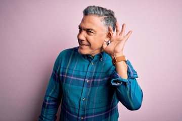 Fototapeta na wymiar Middle age handsome grey-haired man wearing casual shirt over isolated pink background smiling with hand over ear listening an hearing to rumor or gossip. Deafness concept.