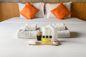 Set of hotel amenities (such as towels, shampoo, soap, drinking glass etc) on the bed. Hotel...