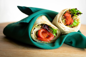A fresh tasty California turkey wrap in a green napkin cloth; showcased on wood cutting board