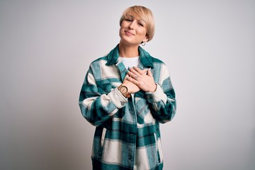 Young blonde woman with short hair wearing casual retro green shirt over isolated background smiling with hands on chest with closed eyes and grateful gesture on face. Health concept.