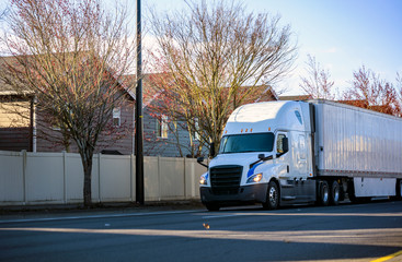 White long haul big rig semi truck transporting commercial cargo in dry van semi trailer running on...