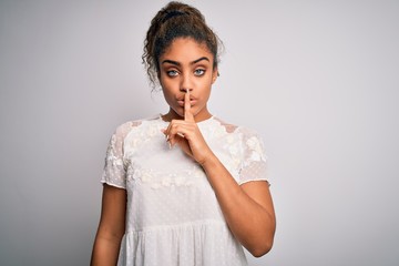 Fototapeta na wymiar Young beautiful african american girl wearing casual t-shirt standing over white background asking to be quiet with finger on lips. Silence and secret concept.