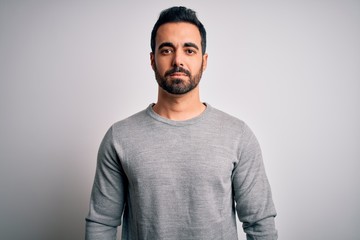 Obraz premium Young handsome man with beard wearing casual sweater standing over white background Relaxed with serious expression on face. Simple and natural looking at the camera.