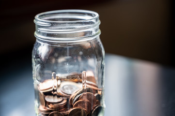 Glass tip jar partly full of loose coin change