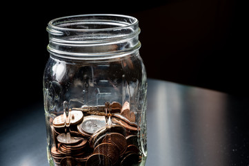 Glass tip jar partly full of loose coin change