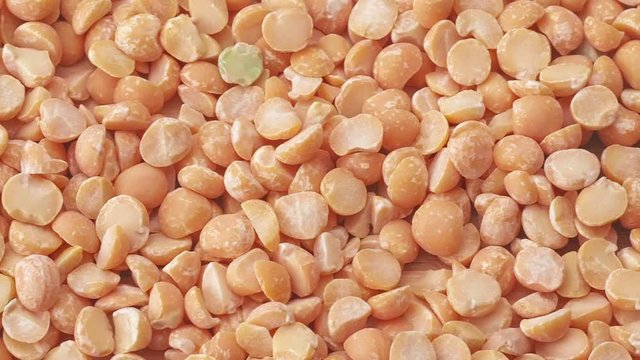 Heap of yellow uncooked split peas, close shot. Dolly shot pile of yellow peas, abstract background. Texture of split peas, close up view