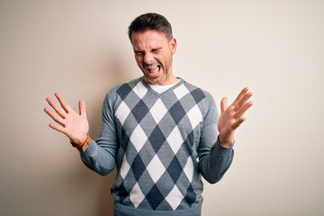 Young handsome man wearing casual sweater standing over isolated white background celebrating mad...