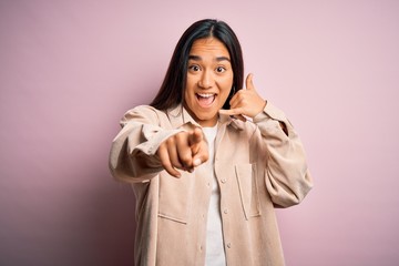 Young beautiful asian woman wearing casual shirt standing over pink background smiling doing...