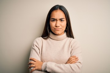 Young beautiful asian woman wearing casual turtleneck sweater over white background skeptic and nervous, disapproving expression on face with crossed arms. Negative person.
