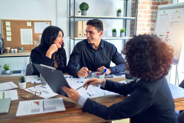 Fototapeta premium Group of business workers smiling happy and confident. Working together with smile on face reading documents and speaking at the office