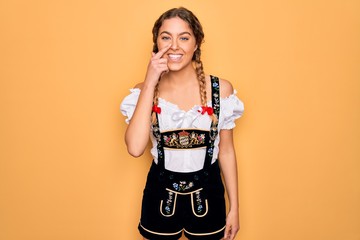 Young beautiful blonde german woman with blue eyes wearing traditional octoberfest dress Pointing...