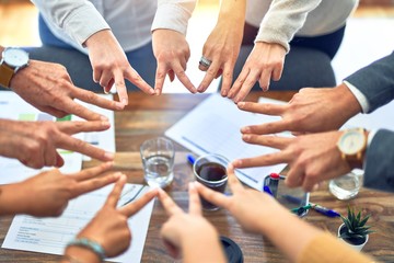 Obraz premium Group of business workers standing doing symbol with fingers together at the office
