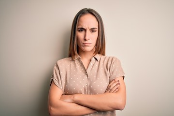 Young beautiful woman wearing casual shirt standing over isolated white background skeptic and nervous, disapproving expression on face with crossed arms. Negative person.