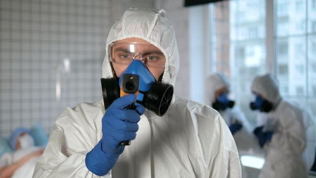 Doctor protective suit using pyrometer to measure temperature of a person behind the camera.