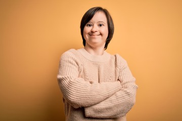 Young down syndrome woman wearing casual sweater over yellow background happy face smiling with crossed arms looking at the camera. Positive person. © Krakenimages.com