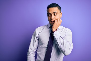 Young brazilian businessman wearing elegant tie standing over isolated purple background looking stressed and nervous with hands on mouth biting nails. Anxiety problem.
