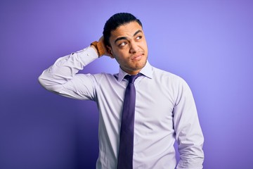 Young brazilian businessman wearing elegant tie standing over isolated purple background confuse and wondering about question. Uncertain with doubt, thinking with hand on head. Pensive concept.