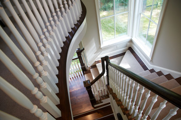 Beautiful interior curved staircase with dark wood and white spindles