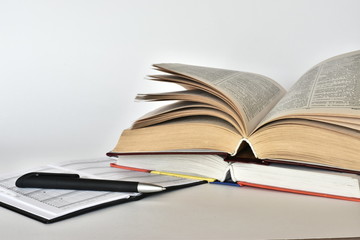 Simple composition of hardback books, raw books on wooden deck table and white background. Back to school. Open book. Place for text.