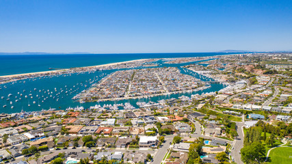 Aerial view of coastal homes in Newport Beach harbor, Orange County, California on a sunny day with boats in the water.