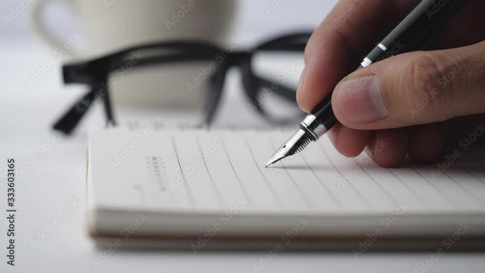 Poster male hands with glasses and cup of coffee write pen in a notebook of tasks and goals to work on a wh