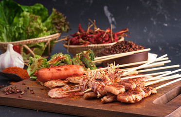 Group of Mala grilled barbecue (BBQ) with Sichuan pepper, Hot and spicy and delicious street food on wood board and ingredients ( Chilli,Sichuan pepper ,Garlic) food on black background.