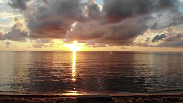 Drone shot descending to reveal Miami Beach lifeguard tower with calm waters and sunrise behind