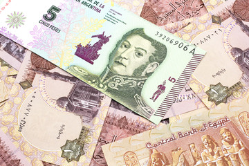 A five peso bank note from Argentina on a background of Egyptian one pound bank notes close up