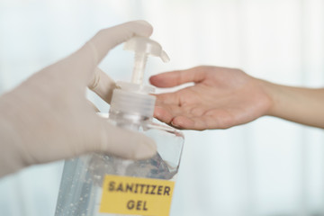 hands using wash hand sanitizer gel pump dispenser. transparent sanitizer in pump bottle, for killing germs, bacteria and virus.