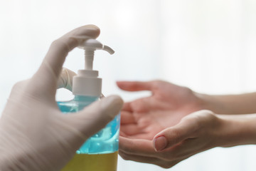 Fototapeta na wymiar hands using wash hand sanitizer gel pump dispenser. transparent sanitizer in pump bottle, for killing germs, bacteria and virus.