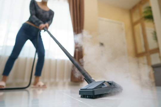 Woman washes the floor with a steam mop.