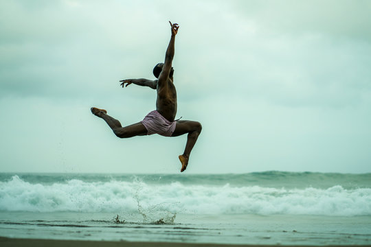 dance choreographer and dancer doing ballet beach workout - young attractive and athletic black African American man dancing outdoors doing beautiful performance - Powered by Adobe