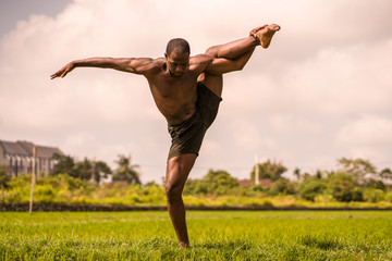 ballet dancer and choreographer workout - young athletic and fit black African American man dancing free outdoors on tropical rice field background in fitness  body expression concept