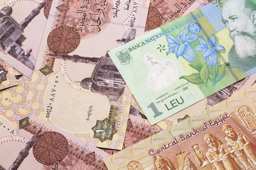A close up image of a green Romanian one leu bank note on a background of Egyptian one pound bank notes