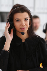 Three call centre service operators at work. Portrait of smiling pretty brunette woman at workplace...