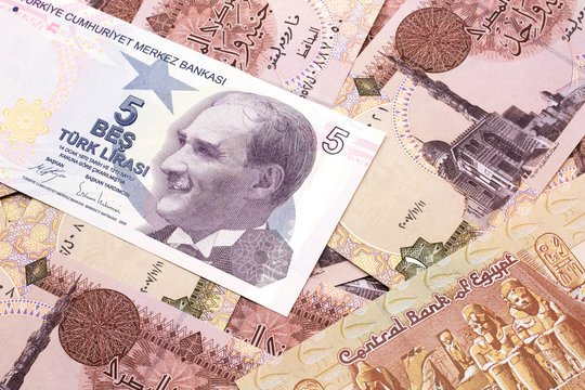 A close up image of a purple five Turkish lira bank note on a background of Egyptian one pound bank notes in macro