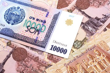 A close up image of a ten thousand Uzbek som bank note on a background of brown, Egyptian one pound bank notes bills in macro