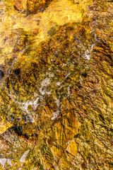 Texture of brown rocks affected by sea wave next to a tropical beach