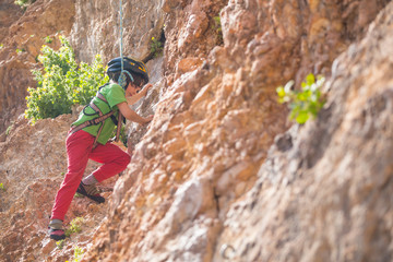Obraz premium The child in helmet is climbing on a natural terrain.