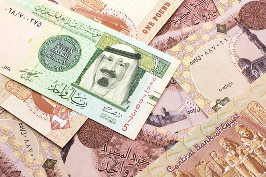 A close up image of a one riyal bank note from Saudi Arabia on a background of Egyptian one pound bank notes in macro