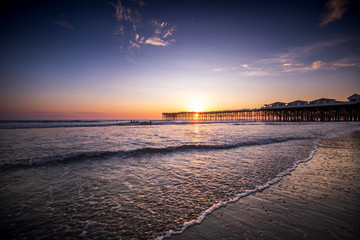 Sunset over the Pier in Pacific Beach, California on a warm cloudy summer evening.