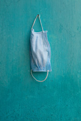 Medical face mask hanging on a nail on a blue wall, Corona, Covid-19, pandemic