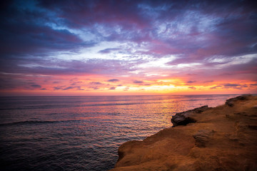 The sky erupts in vibrant colors, as the sun sets over the Pacific Ocean, at Sunset Cliffs in San Diego, California.