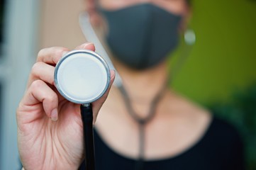 Asian woman wearing facial mask for protection from air pollution or virus epidemic and holding Stethoscope in her hand, she worried about Covid-19 situations.