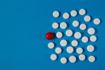 many white pills and one red on a blue background