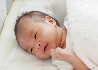 One month old baby in a bed with a dot pattern blanket focusing on the eyes that are not white and have a rash on the cheeks. The mouth of a newborn baby that does not have teeth