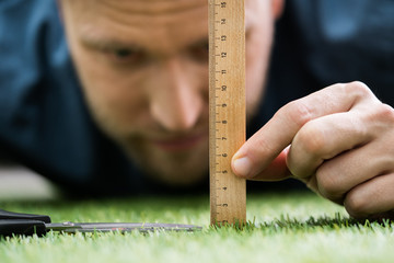 Man Using Measuring Scale While Cutting Grass