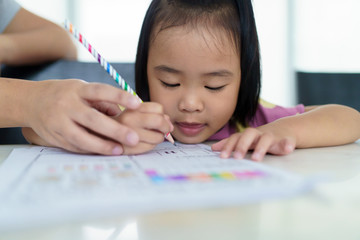 Kindergarten Asian girls doing homework at home with a very determined face